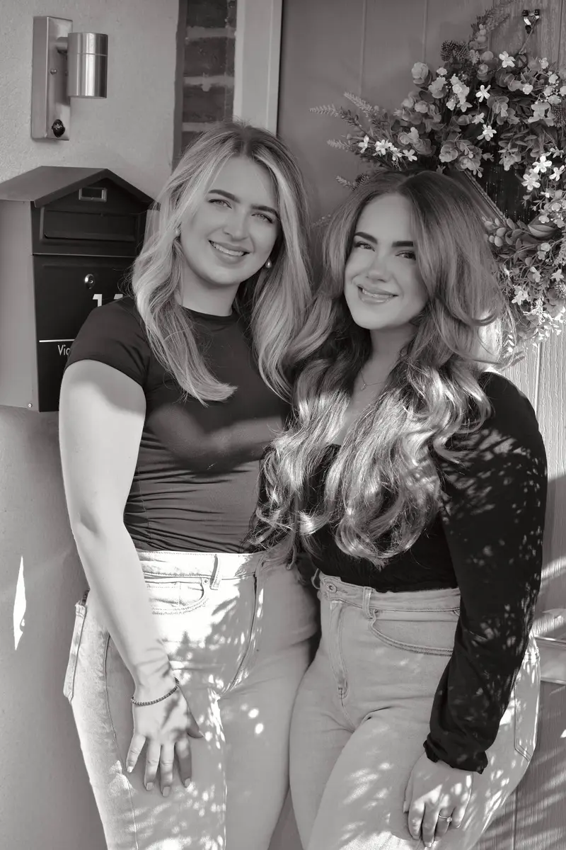 Phoebe Atkinson and Poppy Morris, directors of Heritage Property Consultants, standing together on a front doorstep, black and white photo