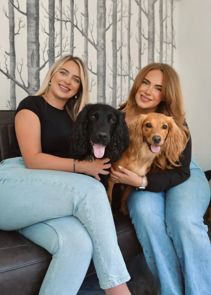 Phoebe and Poppy sitting on a sofa with their two cocker spaniels, Brie and Monty
